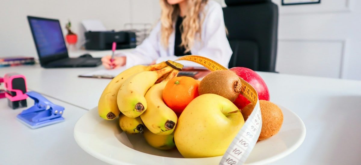 a woman sitting at a desk with a bowl of fruit