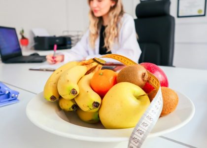 a woman sitting at a desk with a bowl of fruit